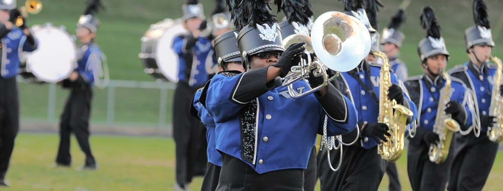 A marching mellophone player with saxophonists in the background